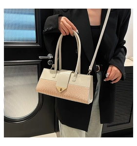 Détail de la texture crocodile crème et de la boucle triangulaire dorée du sac à main