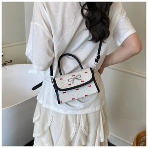 Rear view of a white checkered mini bag with red bow prints and a silver bow clasp