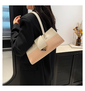 Détail d'un sac bandoulière à motif crocodile avec boucle dorée sur un mannequin