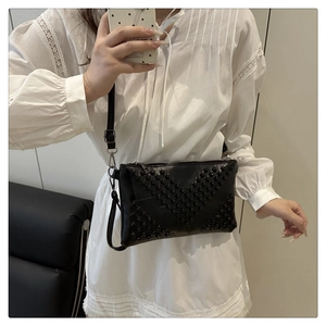 Detail of black crossbody bag featuring vintage rivets in a V-shaped matrix pattern