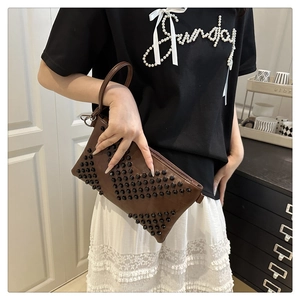 Detail of dark brown envelope clutch with black spherical rivets in a V-pattern