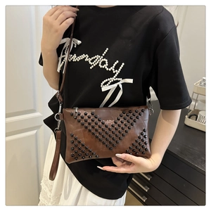 Close-up of brown envelope clutch bag with black rivets and metallic zipper detail