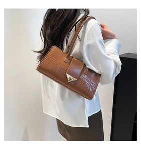 Détail d'un sac à bandoulière en cuir de crocodile marron avec fermoir métallique triangulaire