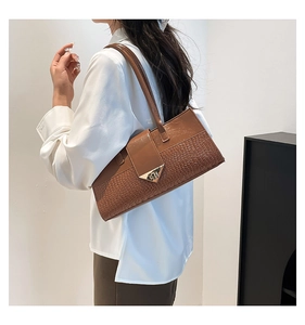 Détail de la couture motif crocodile et boucle triangulaire dorée sur sac à main en cuir