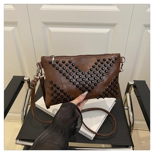 Detail of vintage brown leather envelope bag with black rivets and V-shape pattern