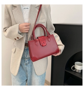 Detail of red crossbody bag featuring crocodile texture contrast on the corners and flap