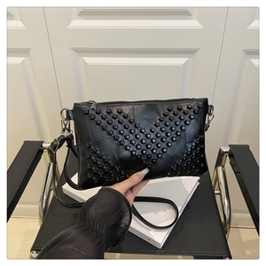 Detail of black PU leather square bag with decorative studs on a minimalist chair