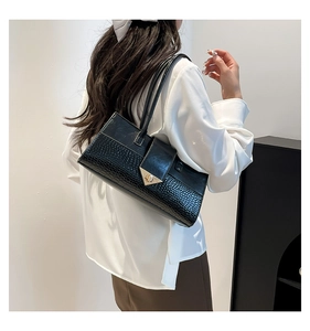 Détail du sac bandoulière noir avec texture crocodile et fermoir triangle doré chic