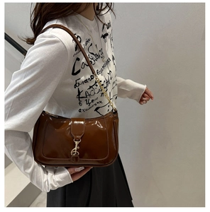 Détail du sac à bandoulière en cuir verni marron foncé avec boucle en métal doré