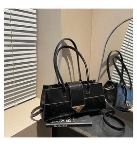 Détail du sac à main noir avec texture crocodile et fermoir triangle doré élégant