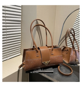 Détail d'un sac à main marron à motif crocodile avec boucle en métal et finition lisse