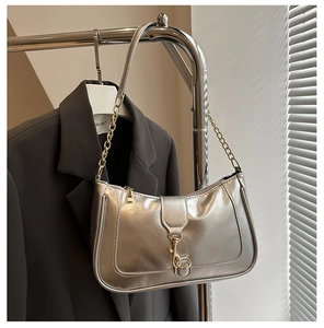 Detail of silver metallic baguette bag with pleated texture and gold chain strap accent