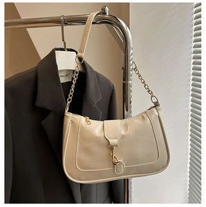 Detail of cream patent leather baguette bag with gold chain strap and metal buckle