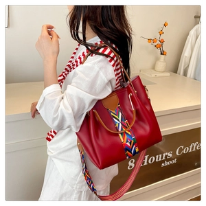 Dettaglio borsa tote in pelle rossa con motivo etnico intrecciato e manici in metallo