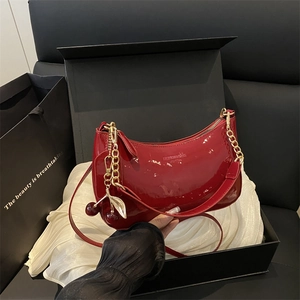 Sac demi-lune rouge verni brillant avec chaîne dorée et pendentif cerise