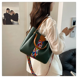 Detailansicht der dunkelgrünen Ledertasche mit bunt besticktem Schultergurt und Ledergriff