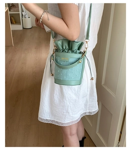 Detail of light green bucket bag showing textured fabric and adjustable leather strap