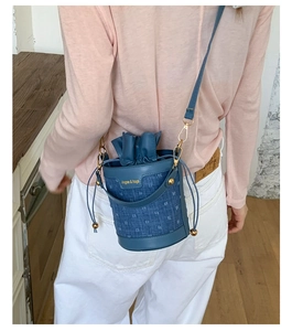 Close-up of a blue denim mini bucket bag with drawstring closure and golden hardware