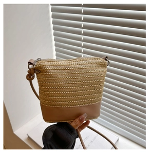Detail showing woven texture and brown leather base of the straw bucket bag