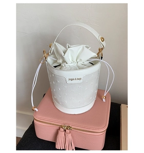 Close-up of white bucket bag with drawstring closure and golden jingpin & bags lettering