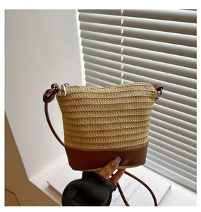 Detail of hand-woven straw bucket bag with leather base and silver metal zipper closure