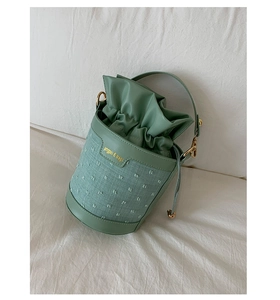 Close-up of green bucket bag with drawstring closure and textured fabric detail