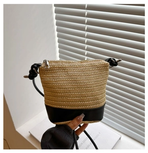 Detail of woven straw bucket bag with black leather bottom and silver metal hardware