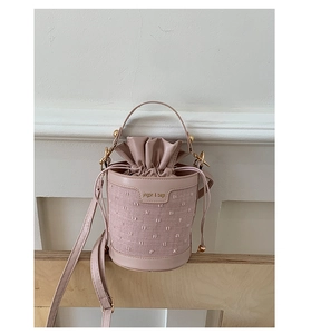 Detail of pink polka dot bucket bag featuring woven leather texture and drawstring closure