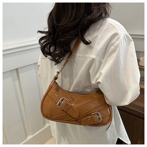 Detailed view of brown retro baguette bag with silver buckles worn by a model
