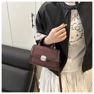 Detail van hoogwaardige bordeauxrode retro tas met metalen sluiting en schouderband