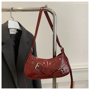 Détail du sac hobo en cuir brillant rouge foncé avec boucles métalliques sur un cintre