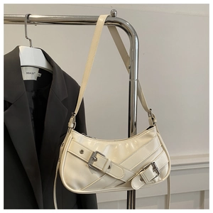 Détail du sac demi-lune blanc cassé au fini brillant avec des boucles en métal rétro