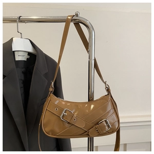 Détail du sac bandoulière en cuir verni marron avec boucles argentées décoratives