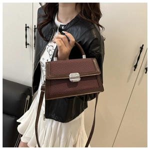 Detail van de bruine crossbodytas met geweven contrastpanelen en zilveren draaisluiting