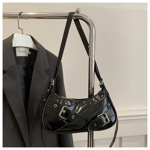 Détail du sac sous le bras noir brillant style punk avec boucles et œillets argentés
