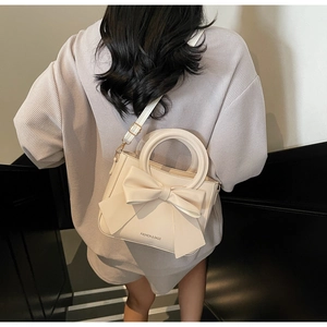 Détail du sac cabas crème avec un grand nœud décoratif et une poignée anneau