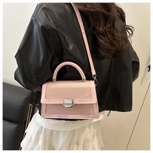 Pink woven square bag with metal lock and leather strap shown on model's shoulder