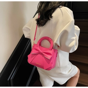 Detailed back view of a bright rose pink crossbody bag with a large decorative 3D bow