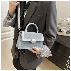 Chique lichtblauwe crossbodytas met geweven flap en zilveren sluiting op grijze blazer