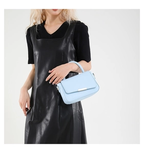 Detail shot of light blue PU leather handbag with metal buckle worn by a fashion model