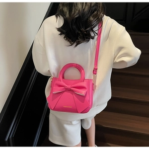Vue arrière d'un mannequin portant un sac à main rose vif orné d'un grand nœud