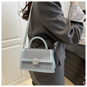 Detail van blauw-grijze geweven crossbodytas met metalen draaisluiting en handvat