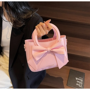 Sac à main rose avec grand nœud et texte Fashion & Bags sur un escalier en bois