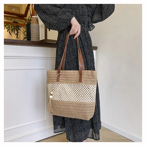 Détail du sac cabas en paille tissée avec anses en cuir et pompon à perles en bois