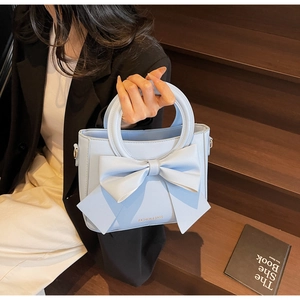 Détail du sac à main bleu clair avec grand nœud décoratif et poignée ronde en métal
