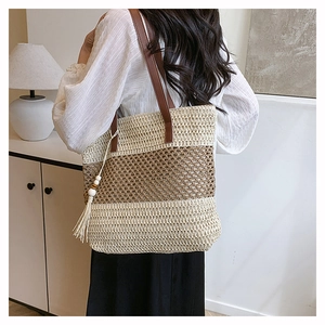 Détail du sac cabas en paille avec anses en cuir marron et pompon à franges perlées