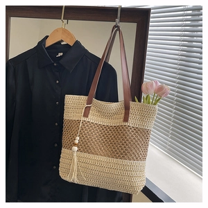Gros plan d'un sac cabas en paille tissée avec rayures contrastées et pompon à franges