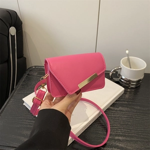 Fashionable magenta crossbody bag with asymmetrical flap and gold metal bar detail
