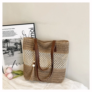 Detailed shot of a woven summer bucket bag with three-tone textures and a tassel charm