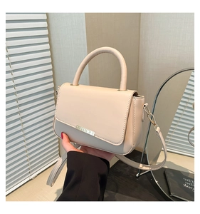 Détail du sac à main crème en similicuir avec fermoir en métal doré et poignée supérieure